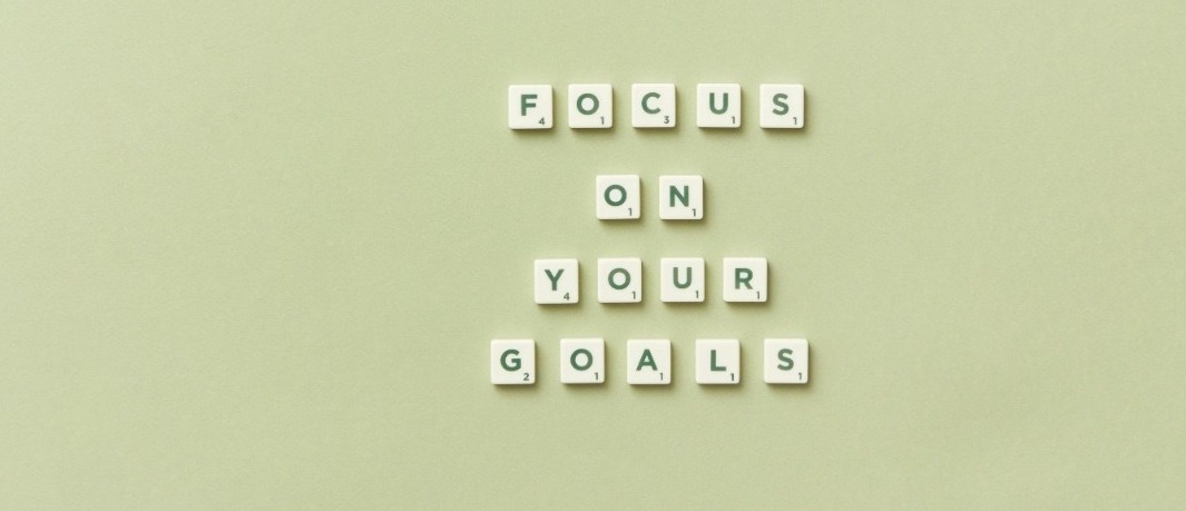 Yellow Background with scrabble letter tiles that say "Focus On Your Goals"